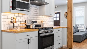 A modern kitchen with white cabinets, a stainless steel stove, and a microwave above. - Newly Remodeled Downtown Helena Home, Sleeps 11 (Helena)
