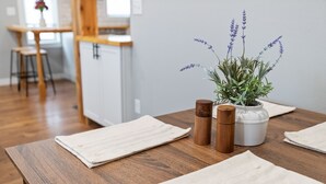 A wooden dining table with white placemats, a potted lavender plant, and two wooden salt and pepper shakers. - Newly Remodeled Downtown Helena Home, Sleeps 11 (Helena)