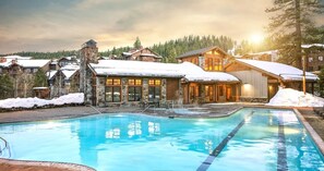 Un resort con piscina, edificios de piedra y techos nevados.