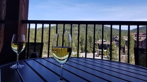 Deux verres de vin blanc sur une table, avec vue sur une chaîne de montagnes boisées.