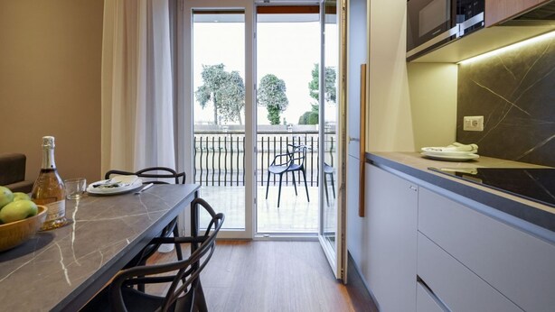 Une cuisine moderne avec un coin repas, une porte-fenêtre coulissante donnant sur un balcon et un four à micro-ondes encastré.