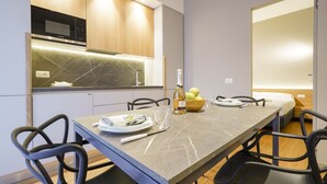 Une cuisine moderne dotée d’un four à micro-ondes encastré, d’un plan de travail en marbre et d’un coin repas avec une longue table et des chaises.