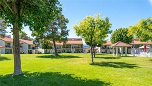 Ein Hotelinnenhof mit Rasen, Bäumen und Gebäuden mit roten Dächern.