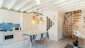 A modern kitchen with white cabinets, a blue-tiled backsplash, a microwave, and a dining area with a striped tablecloth. - GuestHost - Cozy studio with loft of 70 square meters, able to accommodate up to 6 people, located on the third floor of a building without elevator in the heart of Sanremo. The property is equipped with every comfort and a plus is definitely the furnish (Sanremo)