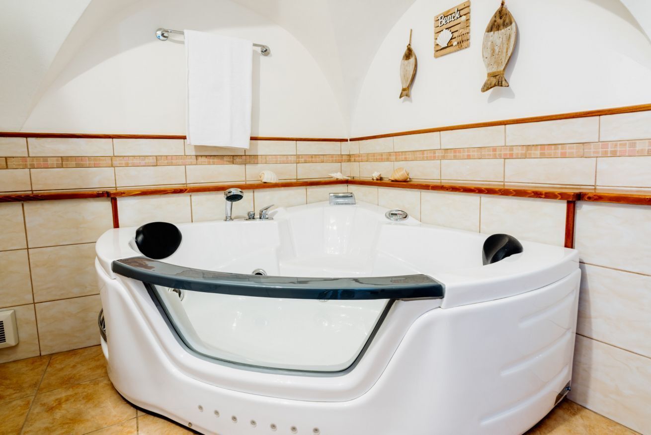 Une salle de bain avec une baignoire blanche, un porte-serviettes et des poissons décoratifs sur le mur.