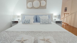 A neatly made bed with starfish towels, a large wall art piece, and a staircase in the background. - GuestHost - Cozy studio with loft of 70 square meters, able to accommodate up to 6 people, located on the third floor of a building without elevator in the heart of Sanremo. The property is equipped with every comfort and a plus is definitely the furnish (Sanremo)
