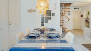 A dining area with a table set for four, a staircase, and a fish decoration on the wall. - GuestHost - Cozy studio with loft of 70 square meters, able to accommodate up to 6 people, located on the third floor of a building without elevator in the heart of Sanremo. The property is equipped with every comfort and a plus is definitely the furnish (Sanremo)