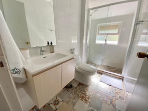 A bathroom with a white sink, toilet, and shower area. - CIPRES Ecolodge & Spa (Frutillar)