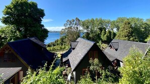 A coastal property with multiple cabins, each featuring a steeply pitched roof and surrounded by lush greenery. - CIPRES Ecolodge & Spa (Frutillar)