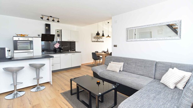 Una cocina moderna con zona de comedor, un sofá gris y una mesa de centro.