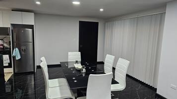 A modern dining area with a black marble table, white chairs, and a black cabinet.