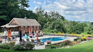 Ein Haus mit Swimmingpool, umgeben von einem Garten mit verschiedenen Pflanzen und Blumen.