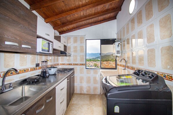 Enjoy a scenic view of the surrounding mountains from this kitchen's window, featuring a stove, sink, microwave, toaster, and dishwasher.