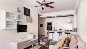 Uma sala de estar moderna com sofá, mesa de centro, TV e estantes embutidas.