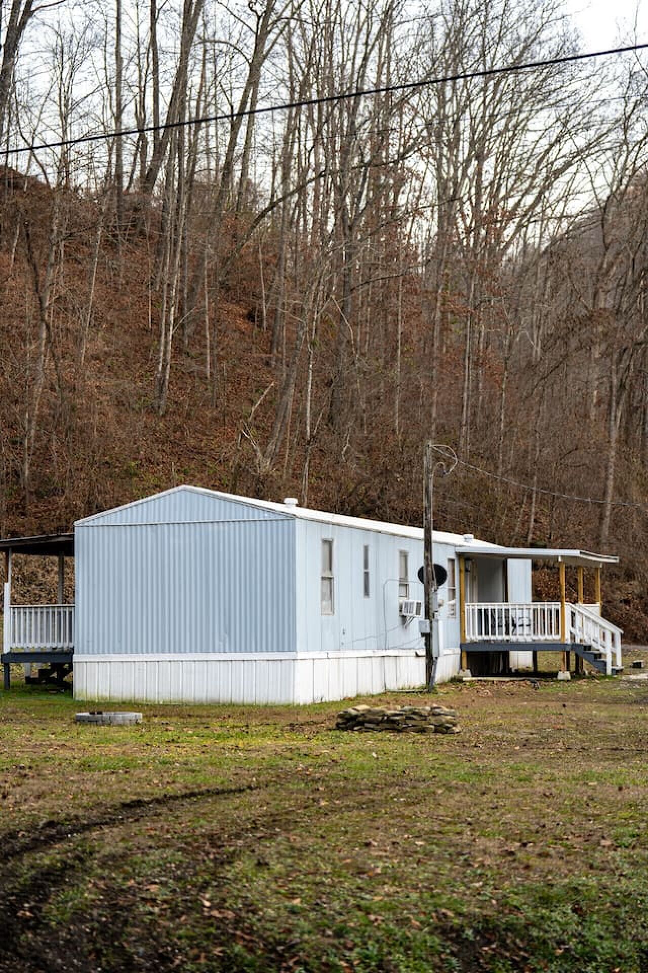 A small, single-story mobile home with a fenced deck and a covered porch.
