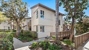 A two-story building with a balcony, surrounded by trees and a garden. - Cozy Condo in the prestigious Ritz Pointe community STR23-0051 (Dana Point)