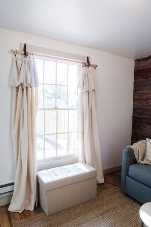 A room with a large window, a bench, a blue sofa, and a wooden wall.