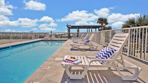 A poolside area with lounge chairs and a covered seating area. - Admiral's Quarter (Kure Beach)