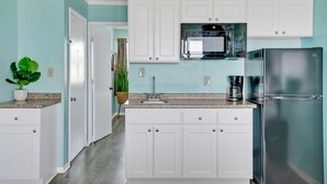 A kitchen with white cabinets, a stainless steel refrigerator, and a microwave. - Admiral's Quarter (Kure Beach)