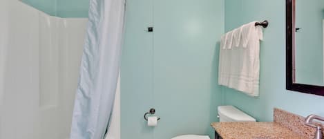 A bathroom with a shower, toilet, sink, and towel rack.