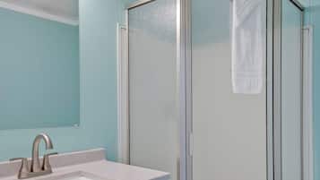 A bathroom with a sink, mirror, and a glass shower enclosure.