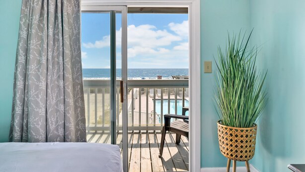 A room with a view of the ocean, a balcony with a pool, and a potted plant. - Admiral's Quarter (Kure Beach)