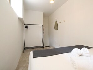 Une chambre d’hôtel équipée d’un lit, d’une serviette, d’un espace douche et d’un miroir fixé au mur.