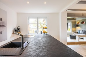 Une cuisine moderne dotée d’un îlot central, d’un évier intégré et d’une fenêtre donnant sur un balcon.