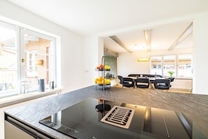 Une cuisine moderne dotée d’un plan de travail noir, d’une cuisinière encastrée et d’un coin repas avec une table et des chaises.