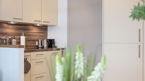 A modern kitchen with white cabinets, a wooden countertop, and a door in the background.