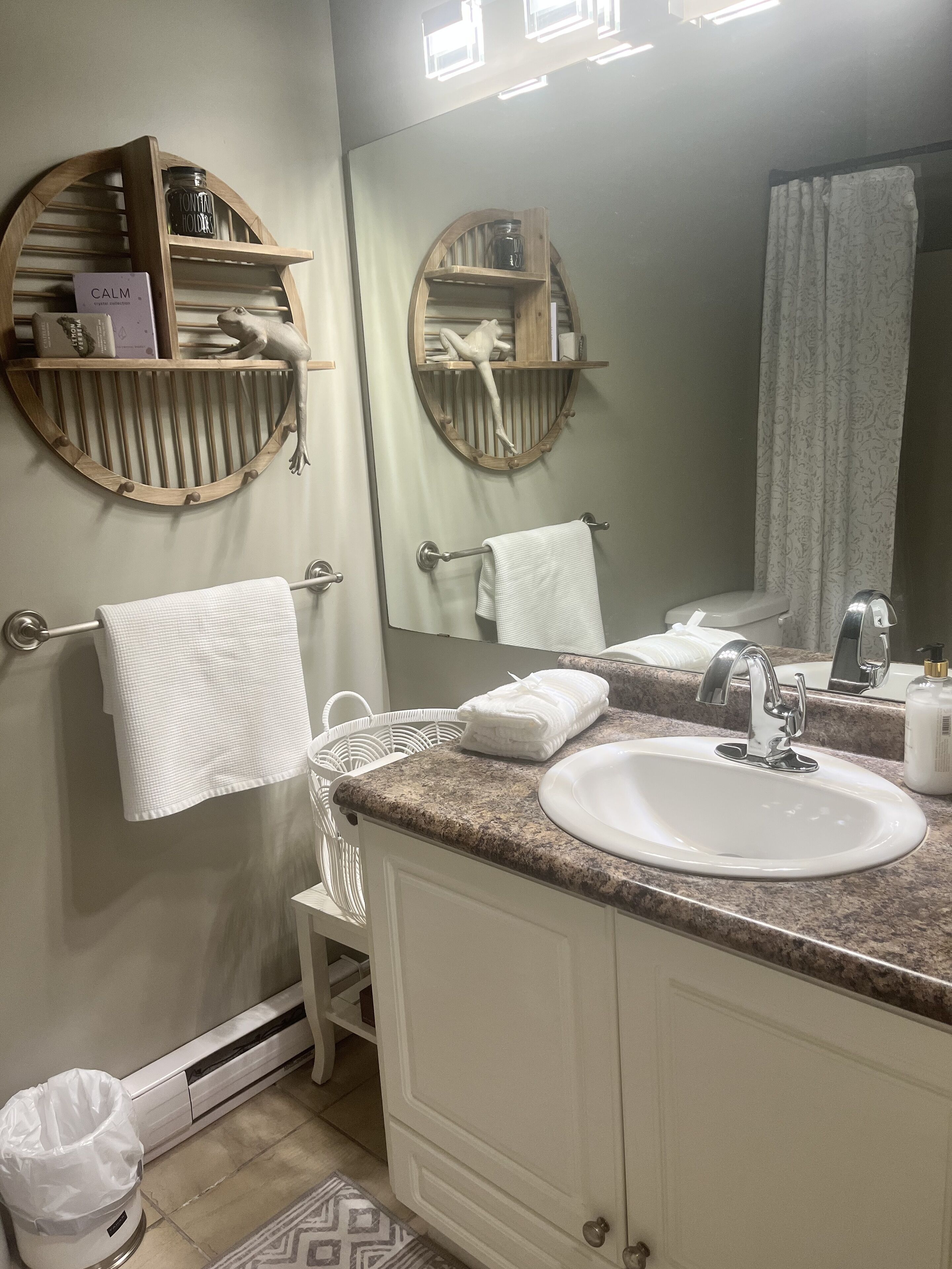 A bathroom with a sink, mirror, towel rack, and shelves with toiletries.