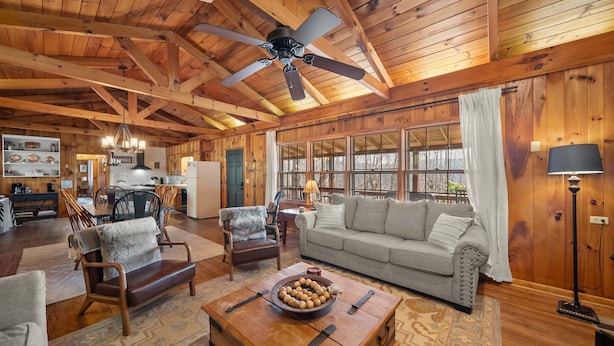 A spacious living area with a wooden ceiling, a large sofa, a coffee table with a fruit bowl, and a dining area in the background. - Great Grandfather View - hot tub, fire pit, family games, all bedrooms on main level, views (Banner Elk)