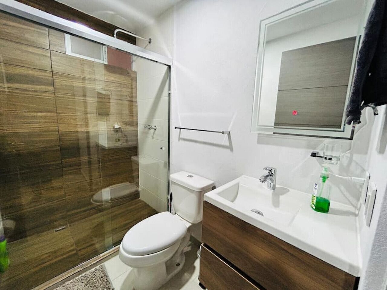 A modern bathroom with a glass-enclosed shower, a toilet, and a sink with a mirror above it.