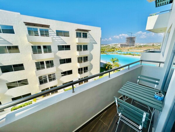 A modern building with multiple balconies overlooking a pool and beach.