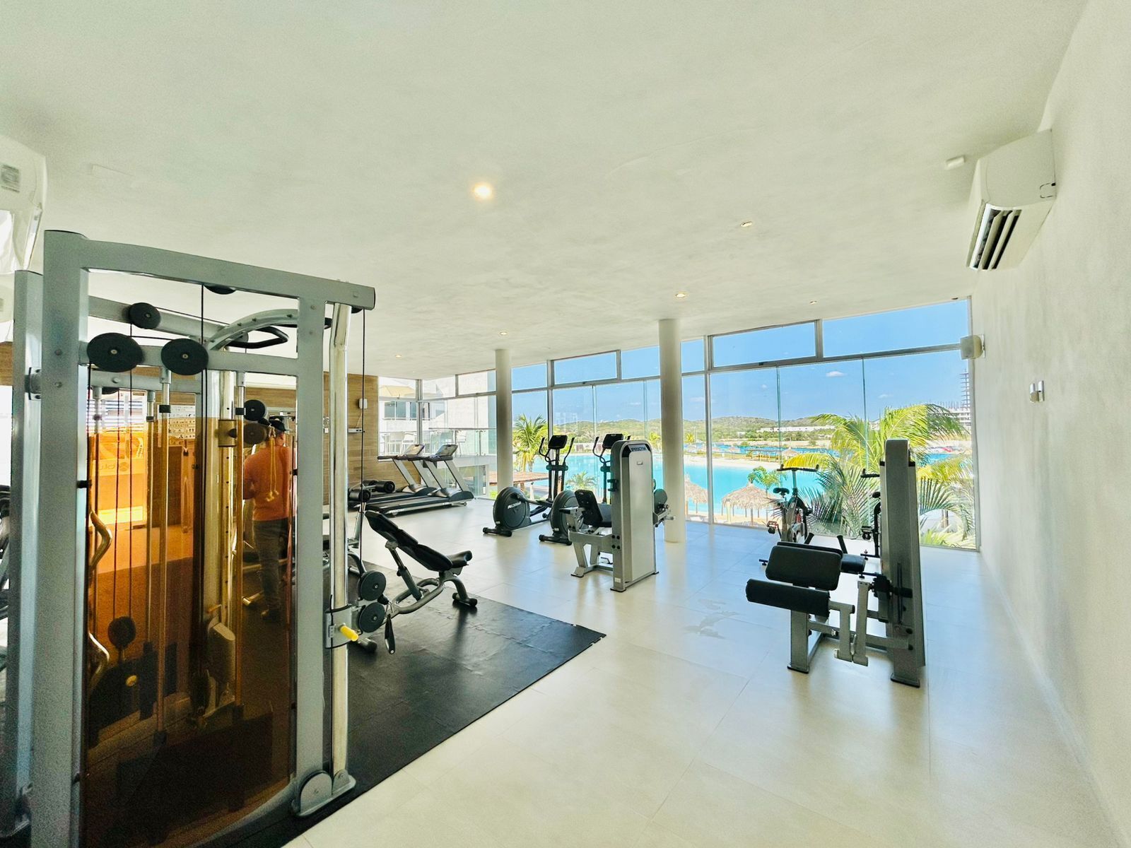 Un gimnasio con equipo cardiovascular, máquinas de pesas y vistas a la playa.
