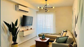 Una sala de estar moderna con televisor de pantalla plana, lámpara de techo, sofá y mesa de centro.