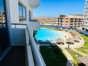 A modern hotel with a pool, a view of the surrounding area, and a clear sky.