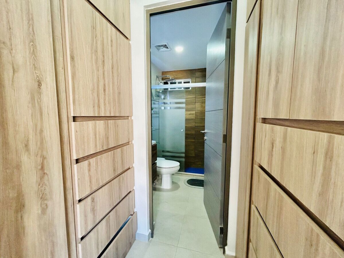 Ein schmaler Flur, der zu einem Badezimmer mit Toilette und Duschbereich führt.