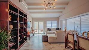 A spacious living room with a high ceiling, a central chandelier, and a large bookshelf. - Villa de Leon, suitable for 14 persons. 5 bedrooms, 5 bathrooms (Noord)