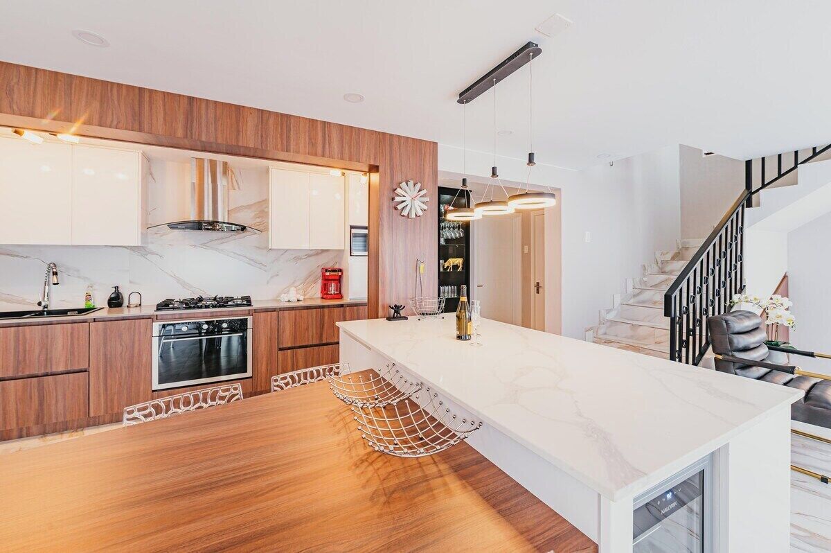 A modern kitchen with wooden cabinets, a marble countertop, and a built-in oven.