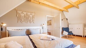 Ein Schlafzimmer mit einem großen Bett, einem Sessel, einem Kleiderschrank und einer Wanddekoration aus Fransen.