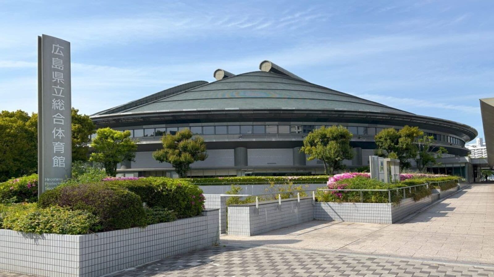 A modern building with a curved roof and a sign indicating it is a sports facility.
