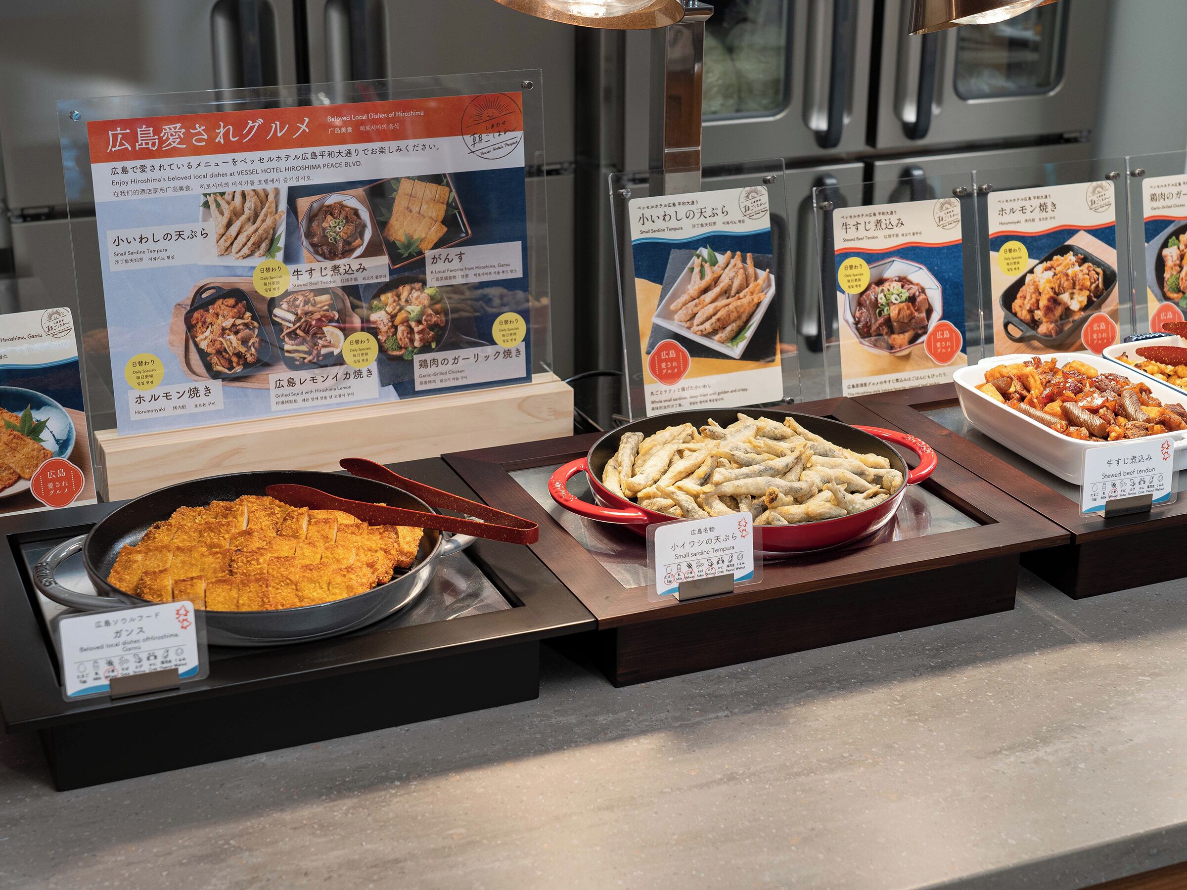 A buffet with various dishes displayed in trays, including fried items and a bowl of rice.