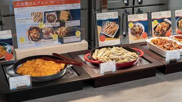 A buffet with various dishes displayed in trays, including fried items and a bowl of rice.