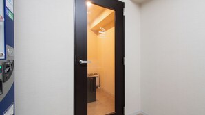 Une porte dotée d’un panneau de verre qui donne sur une pièce portant l’inscription « Salle fumeurs », où l’on peut voir un grille-pain.