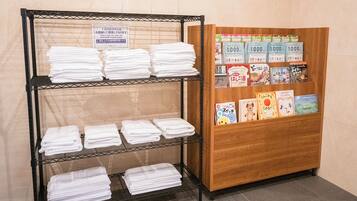 A hotel reception area with a display of neatly folded white towels on shelves and a wooden cabinet with books and brochures.
