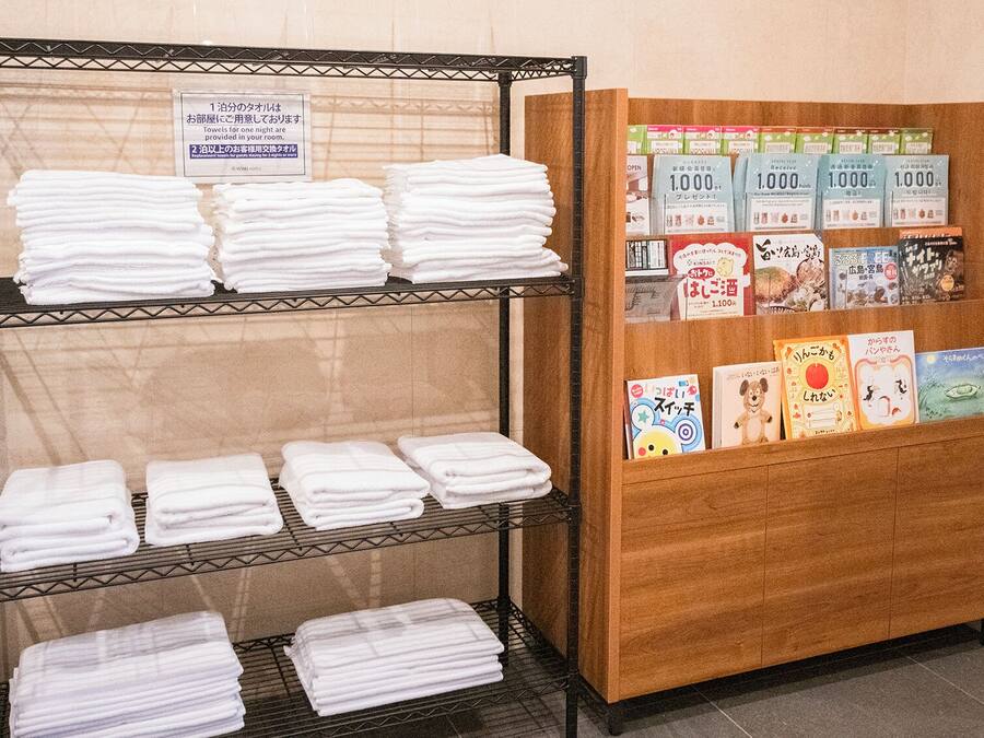 A hotel reception area with a display of neatly folded white towels on shelves and a wooden cabinet with books and brochures.
