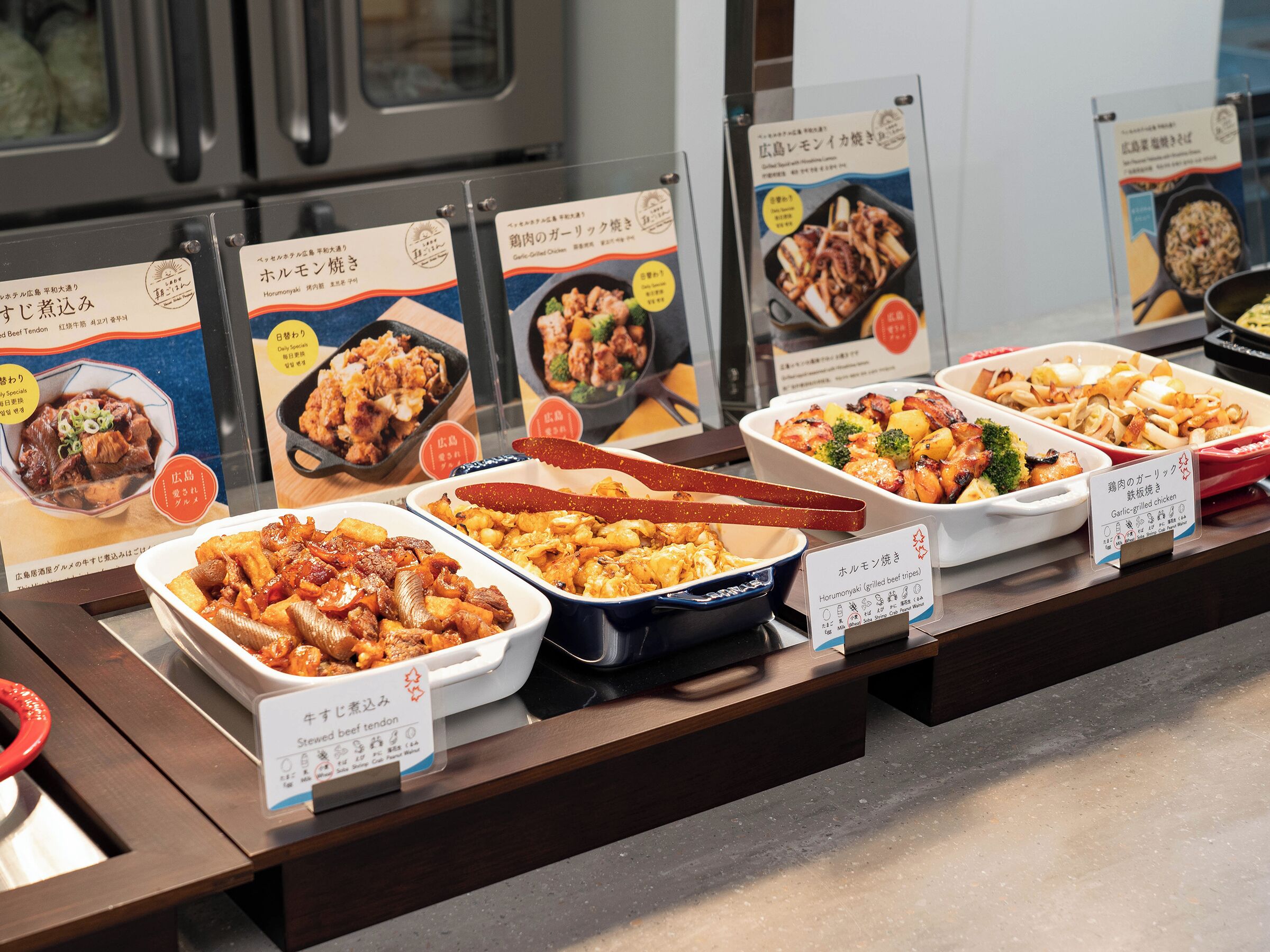 A buffet with various dishes, including beef tenderloin and grilled chicken, displayed in bowls and trays.