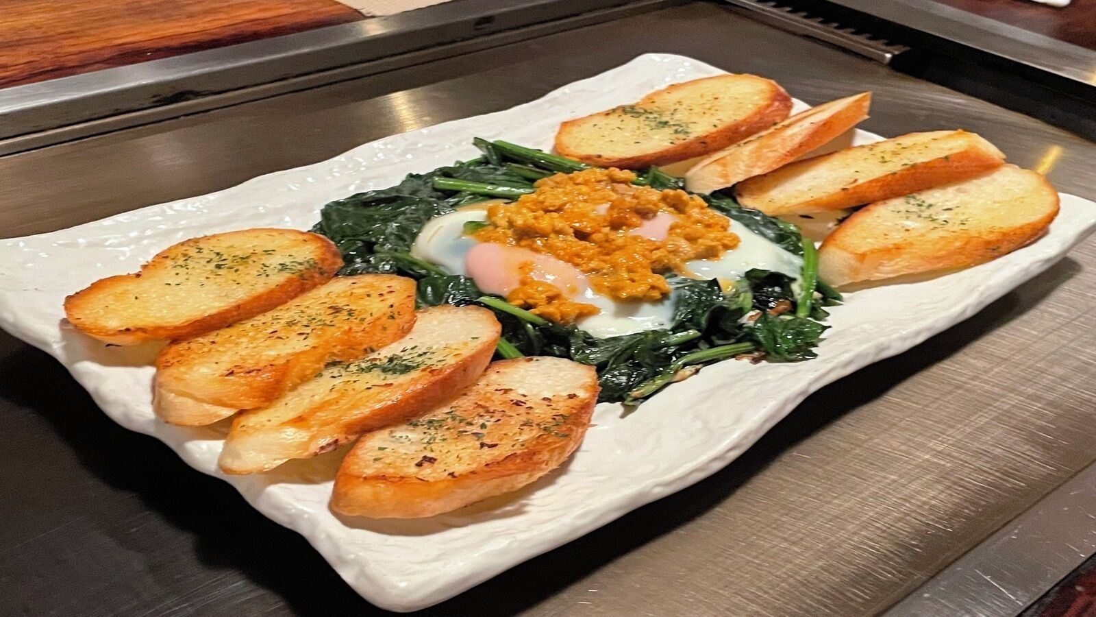 A white plate with scrambled eggs, sautéed greens, and toasted bread.