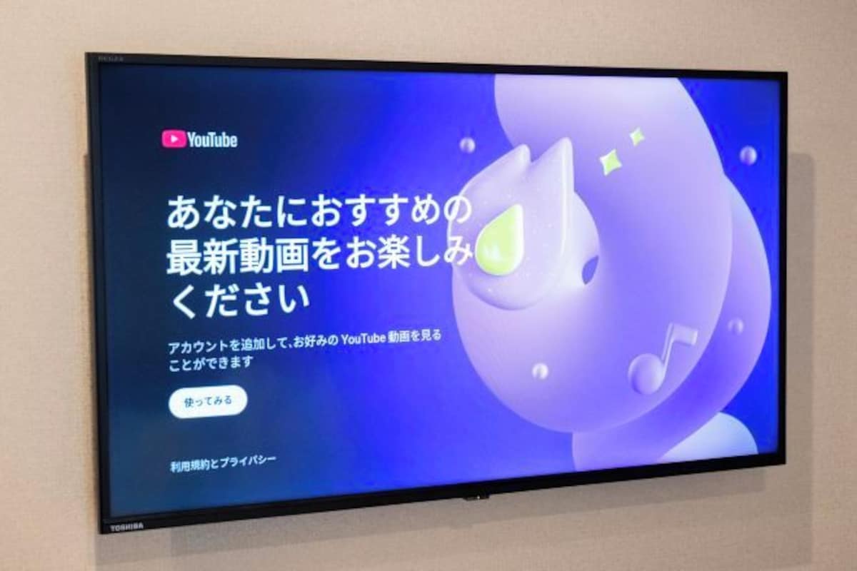 Un téléviseur à écran plat fixé au mur affiche le message d’accueil d’une chaîne YouTube, rédigé en japonais.